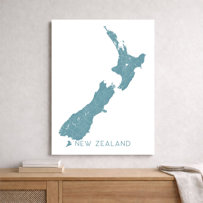 Map of New Zealand on a white wall above a wooden shelf.