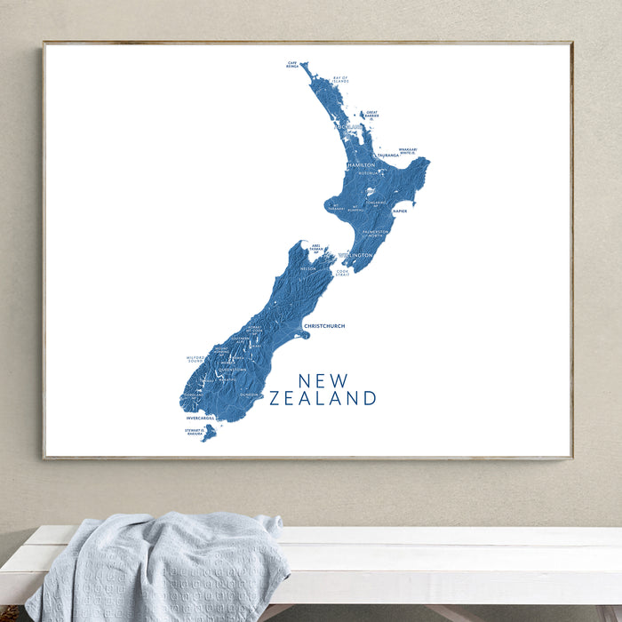 Framed map of New Zealand on a wall above a white bench.