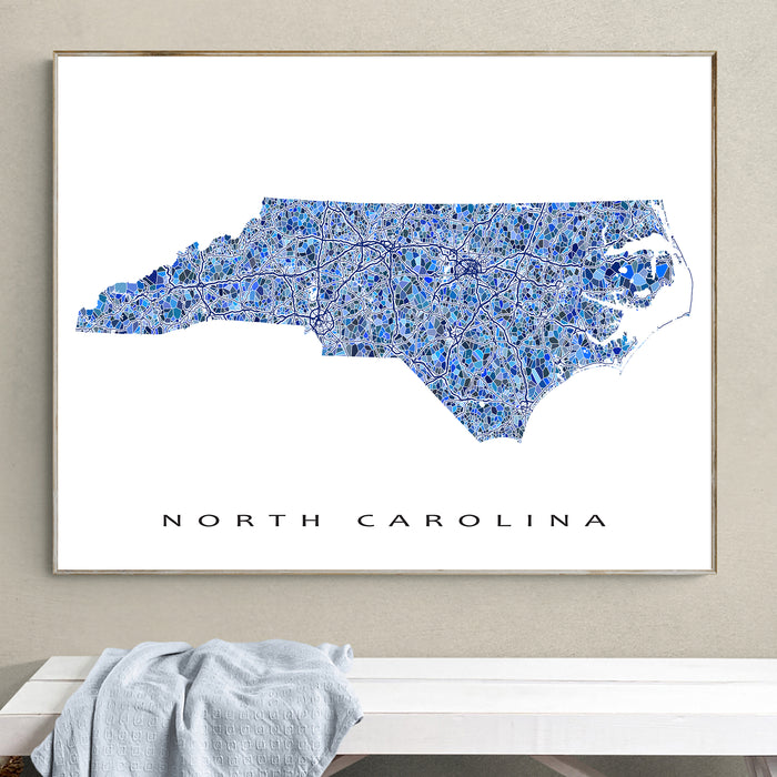 Framed map of North Carolina on a wall above a bench.