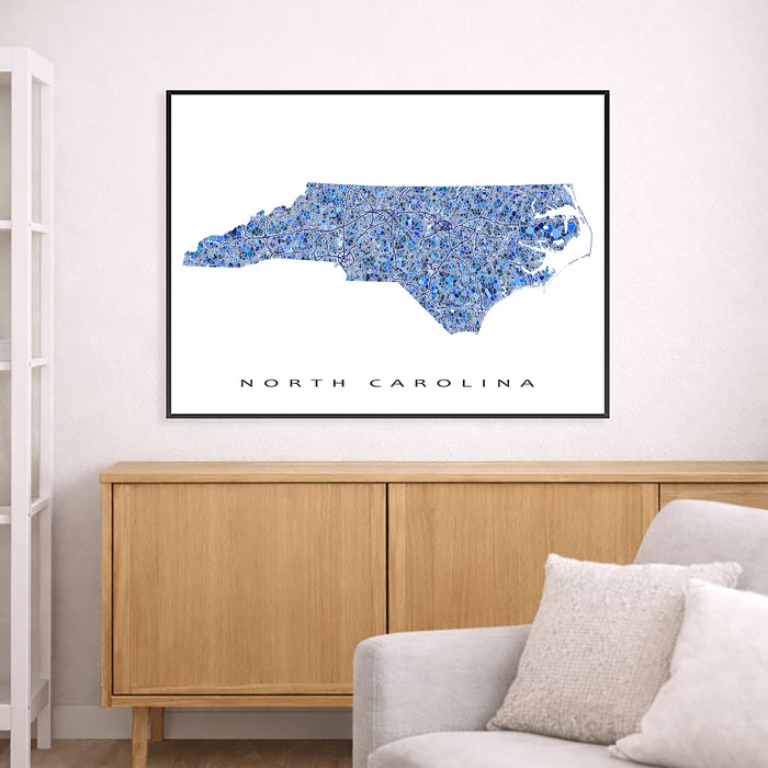 Framed map of North Carolina on a wall above a wooden cabinet and sofa.