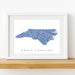 Framed map of North Carolina with a blue mosaic pattern on a white background