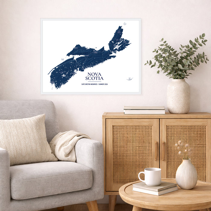 A framed Nova Scotia map print hangs on a light beige wall above a gray armchair and a wooden cabinet in a styled living room setting.