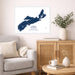 A framed Nova Scotia map print hangs on a light beige wall above a gray armchair and a wooden cabinet in a styled living room setting.