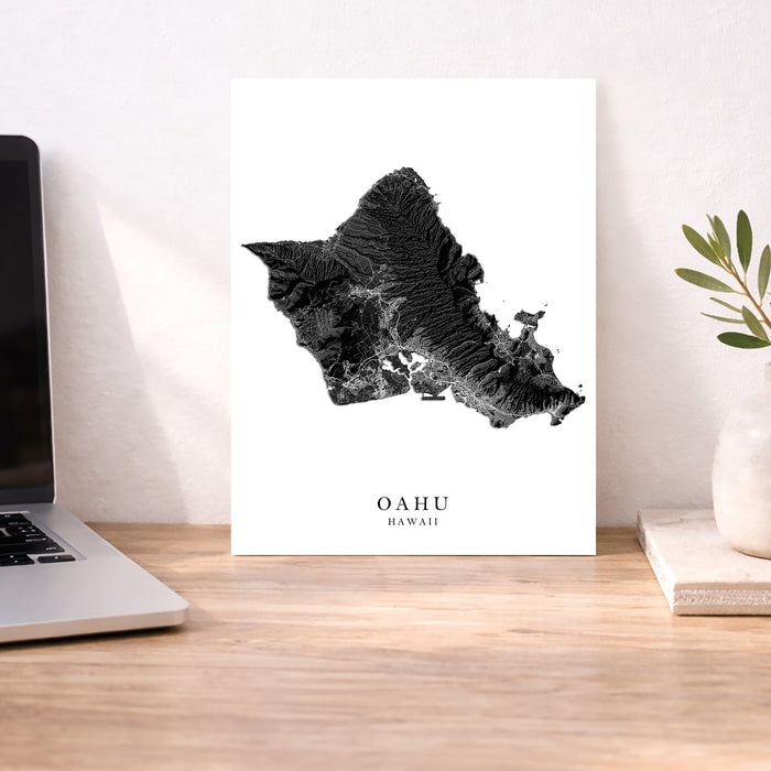 Map of Oahu, Hawaii on a white background with a laptop and plant in the background.
