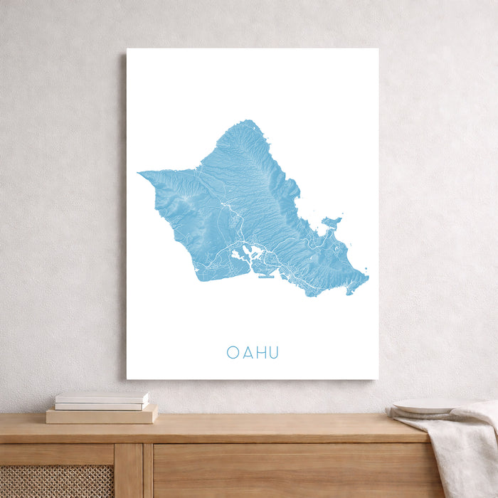 Unframed map of Oahu on a wall above a wooden shelf.