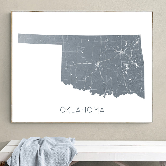 Framed map of Oklahoma on a wall above a white bench.