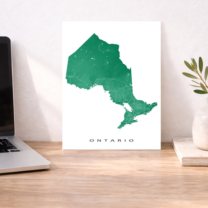Map of Ontario on a white background next to a laptop on a wooden desk.