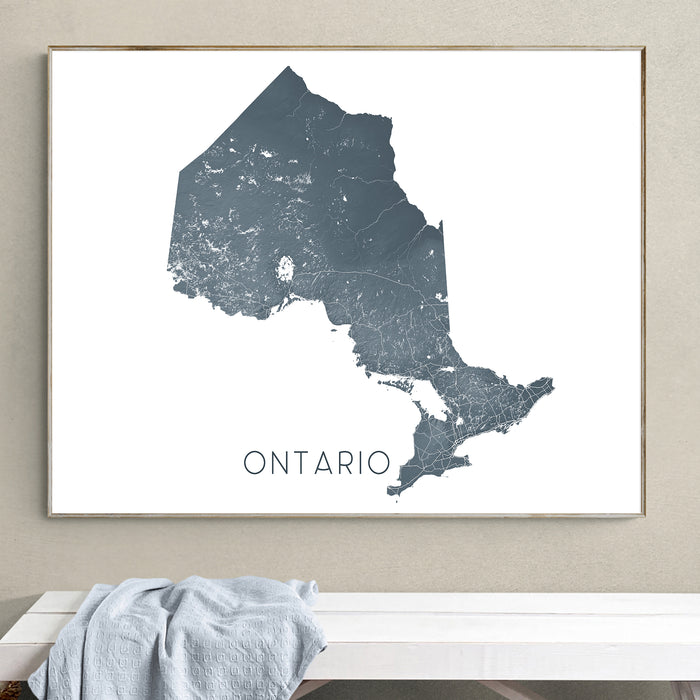 Map of Ontario framed on a wall above a white bench.