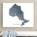 Map of Ontario framed on a wall above a white bench.