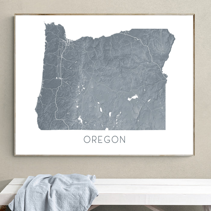 Framed map of Oregon on a wall above a white surface with a gray towel.