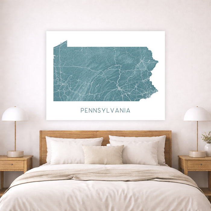 Framed map of Pennsylvania on a wall above a bed in a bedroom.