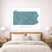 Framed map of Pennsylvania on a wall above a bed in a bedroom.
