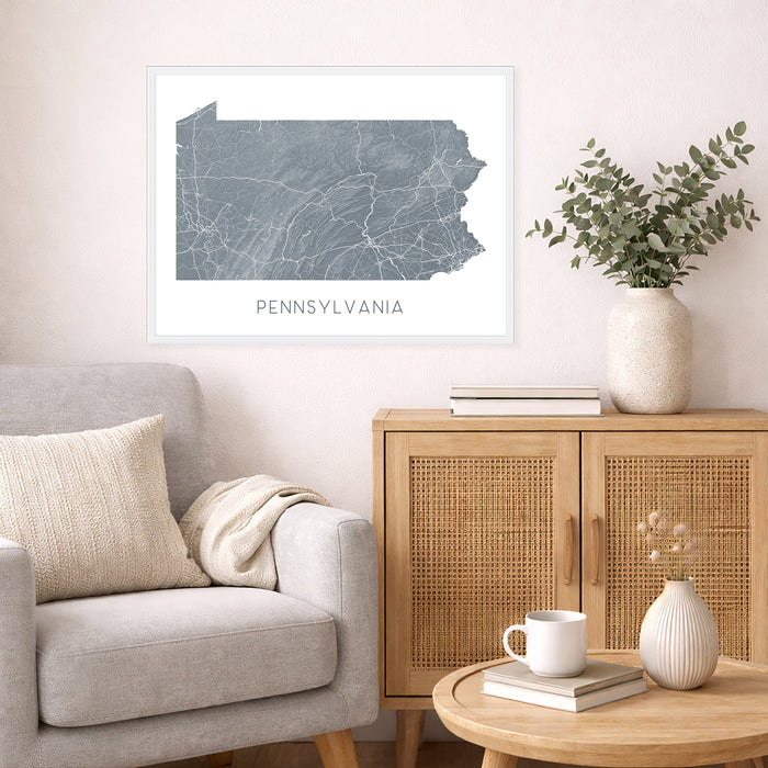 Framed map of Pennsylvania on a wall above a sofa in a living room.