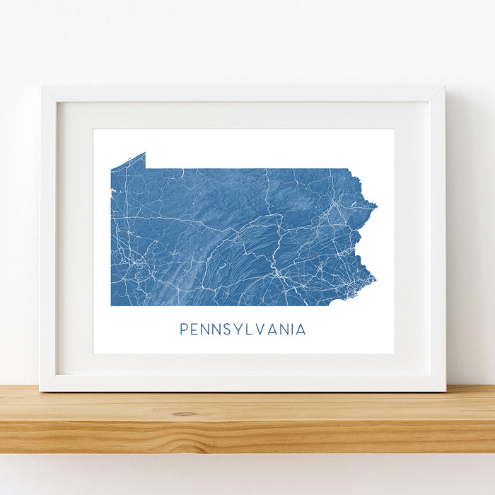 Framed map of Pennsylvania on a wooden shelf with a white background