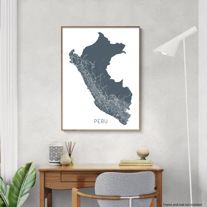 Framed map of Peru on a wall above a desk with decor items.