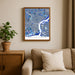 Framed map of Philadelphia on a wall above a beige sofa with a plant beside it.