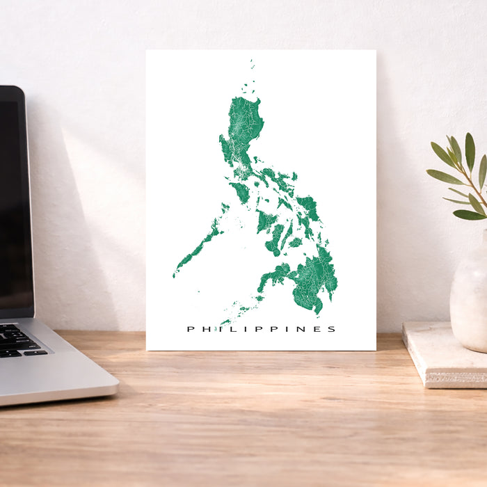 Map of the Philippines on a white background displayed on a wooden desk.