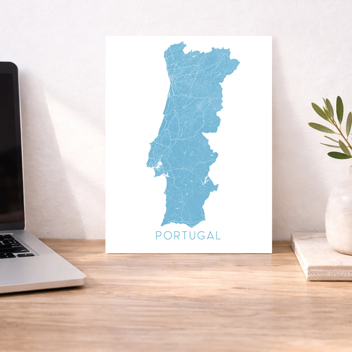 Map of Portugal on a desk with a laptop and plant