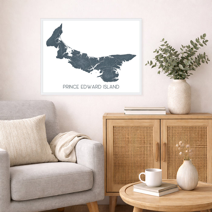 Living room with a map of Prince Edward Island on the wall, a couch, and a side table with a vase and books.