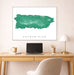 Framed map of Puerto Rico on a wall above a desk with a laptop and lamp.