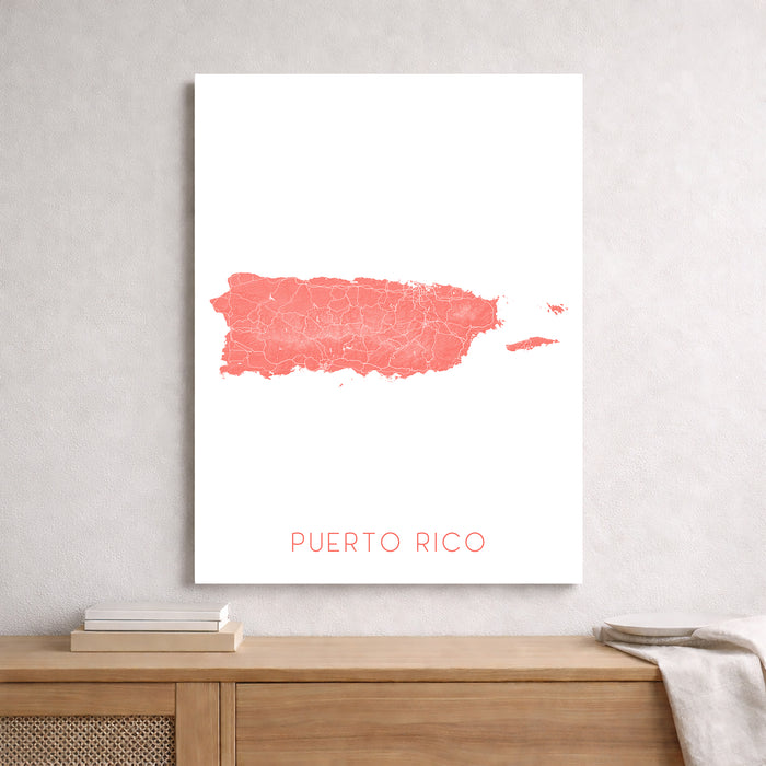 Framed artwork of a pink watercolor map of Puerto Rico on a white wall.