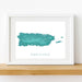 Framed map of Puerto Rico with a white border on a wooden surface.