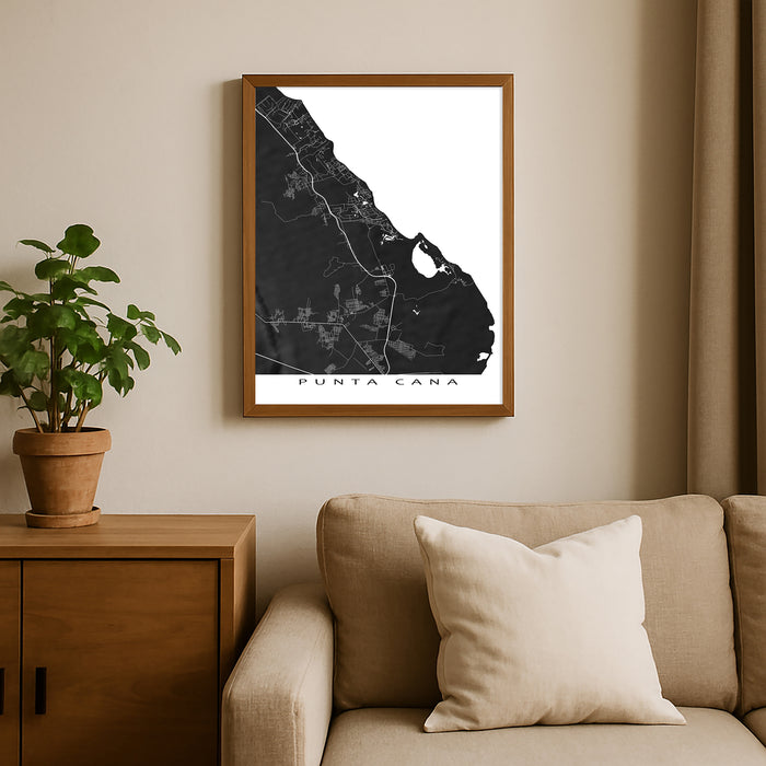 Framed map of Punta Cana on a wall above a beige sofa with a plant beside it.