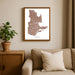 Framed map of Quebec on a wall above a beige sofa with a plant beside it.