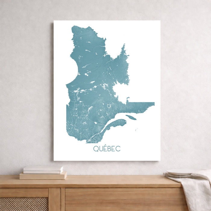 Map of Quebec in blue on a white background, framed and leaning against a light gray wall.