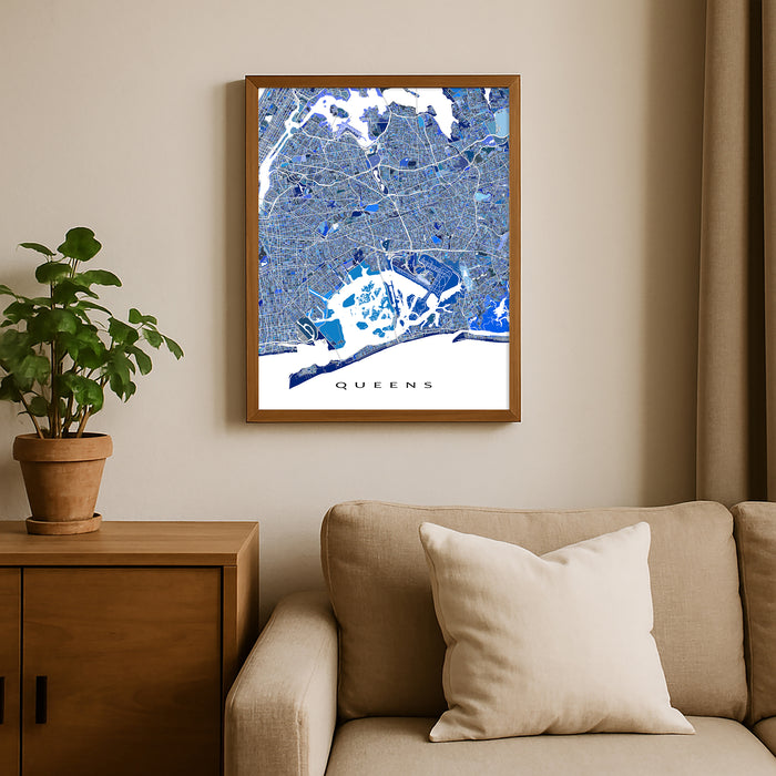 Framed map of Queens on a wall above a beige sofa with a plant beside it.