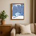 Framed map of Queens on a wall above a beige sofa with a plant beside it.