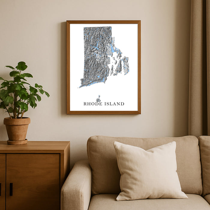 Framed map of Rhode Island on a wall above a sofa with a plant beside it.