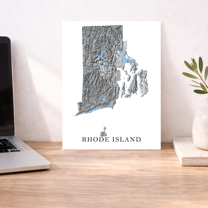 Map of Rhode Island on a desk with a laptop and plant