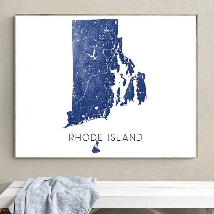 Framed map of Rhode Island on a wall above a white bench.