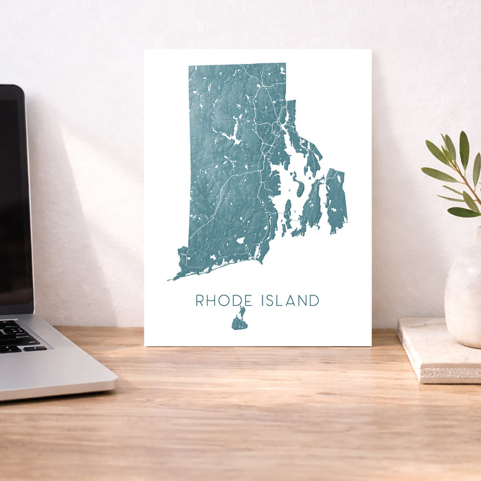 Map of Rhode Island on a desk with a laptop and plant