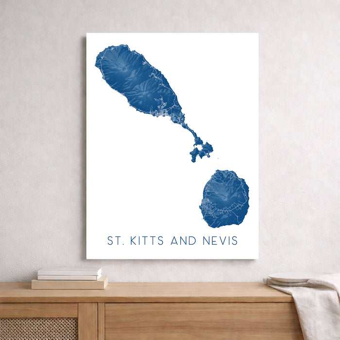 Map of St. Kitts and Nevis on a white background, framed and leaning against a light gray wall.