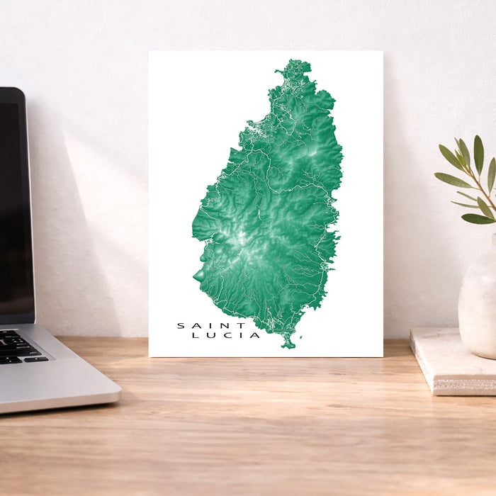 Map of Saint Lucia on a white background next to a laptop and plant on a wooden desk.