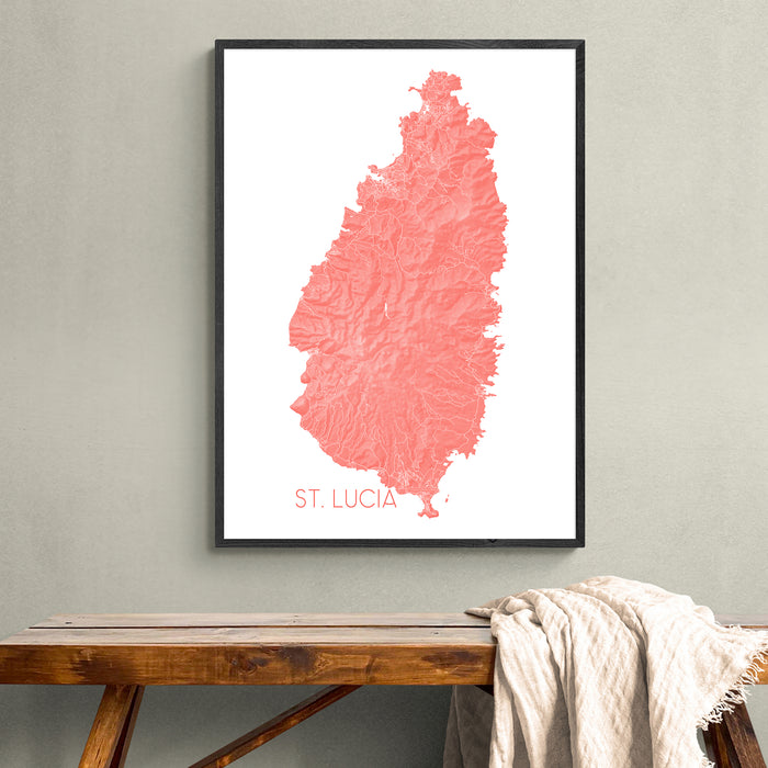 Framed map of St. Lucia in pink on a white background, hanging on a wall above a wooden bench.