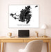 Framed map of Saint Martin on a wall above a desk with a laptop and lamp.