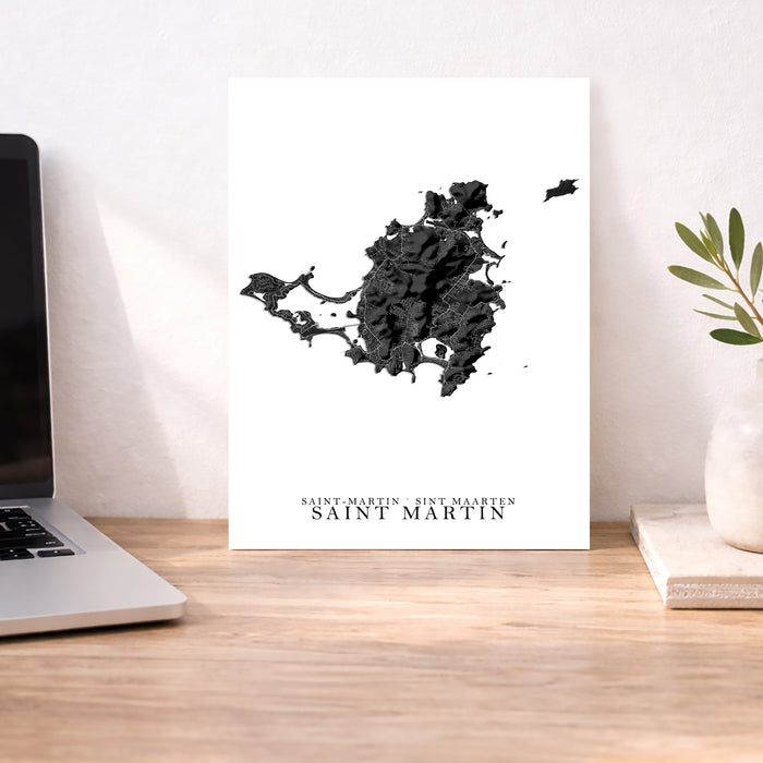 Map of Saint Martin on a white background next to a laptop on a wooden desk.