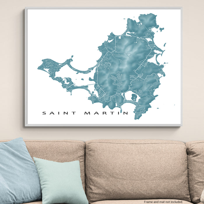 Framed map of Saint Martin on a wall above a beige sofa with light blue pillows.