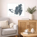 Living room with a map of Saint Martin on the wall, a couch, and a side table with a plant and books.