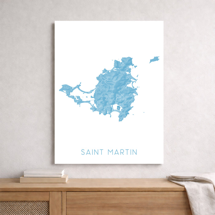 Map of Saint Martin on a white wall above a wooden shelf.