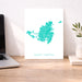 Map of Saint Martin on a white background displayed on a desk with a laptop and plant.