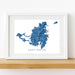 Framed map of Saint Martin on a white wall with a wooden shelf.