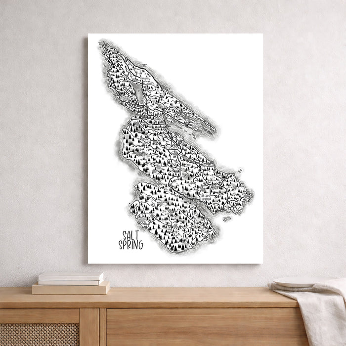 Black and white map of Salt Spring Island on a white wall above a wooden shelf.