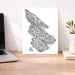 Map of Salt Spring Island on a white background, displayed on a wooden desk with a laptop and plant.