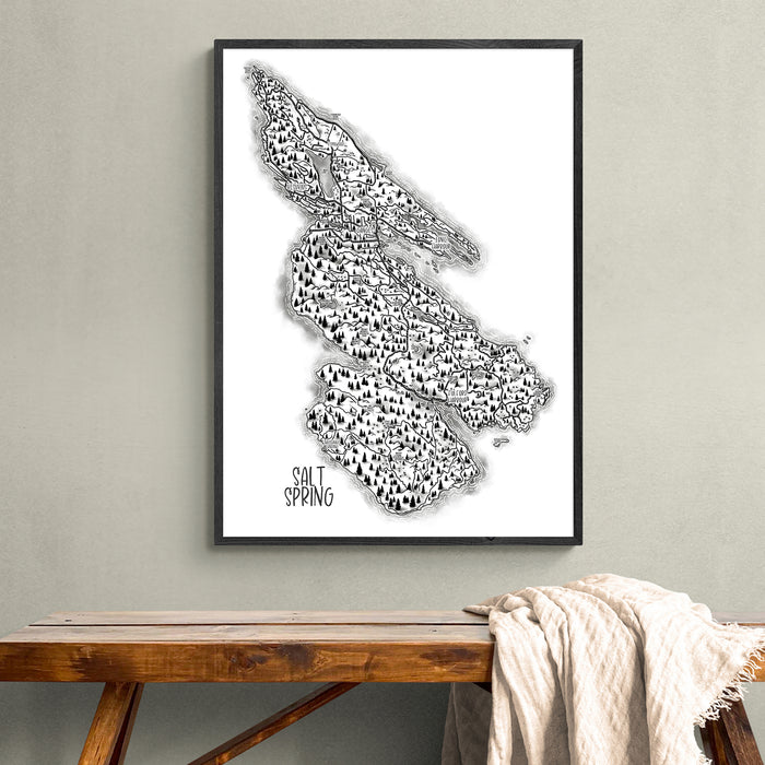 Framed black and white map of Salt Spring Island on a wall above a wooden bench.