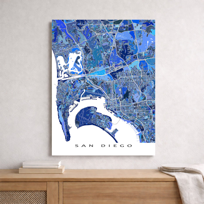 Map of San Diego in blue tones on a white wall above a wooden shelf.