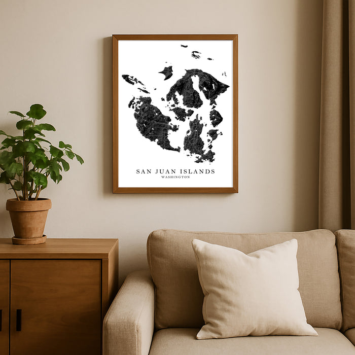 Framed map of San Juan Islands on a wall above a sofa with a plant beside it.